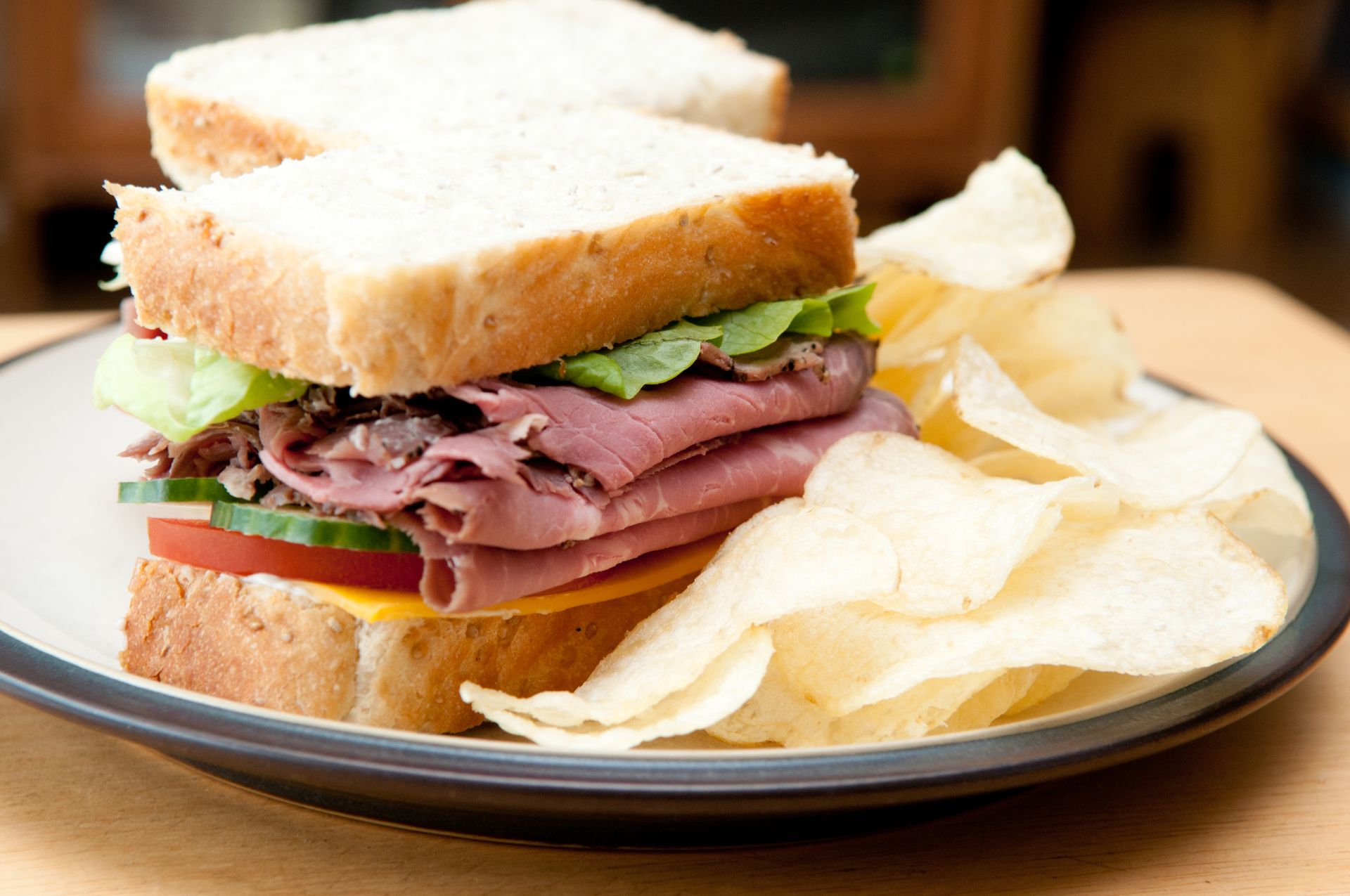 Photo of a roast beef sandwich and potatoes chips on a plate.